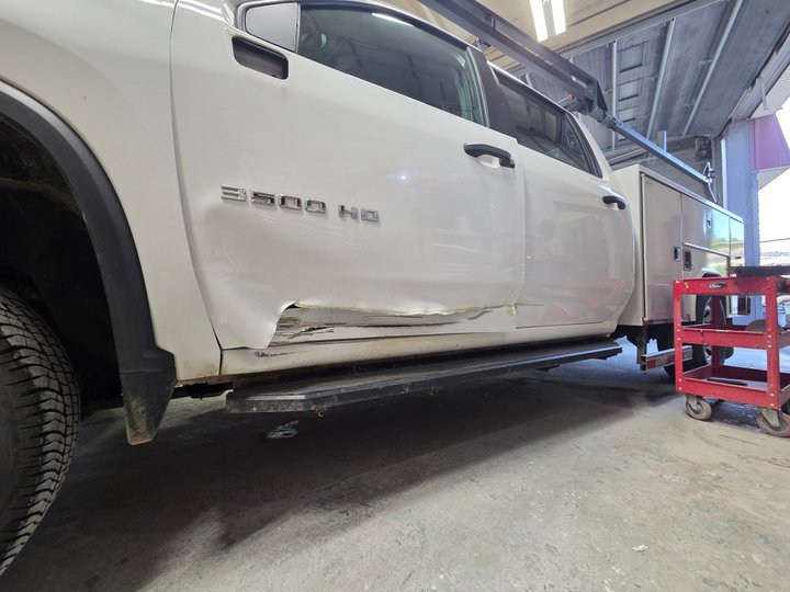 Before: driver's-side collision damage on a white Chevrolet 3500HD work truck