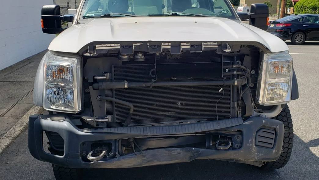 White utility truck with its front end stripped for collision repair at Mickey's Auto Body in Kearny, NJ